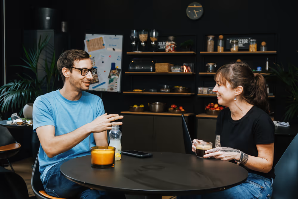 Two employees chatting at a desk in the office